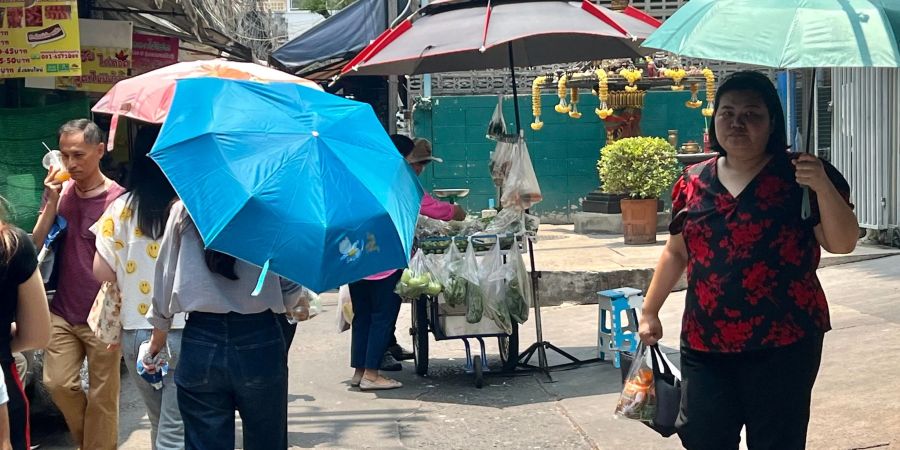 Menschen schützen sich in Bangkok mit Schirmen vor der extremen Hitze und vor der Sonne. Nicht nur in Thailand, sondern auch auf den Philippinen leiden die Menschen derzeit unter den hohen Temperaturen.