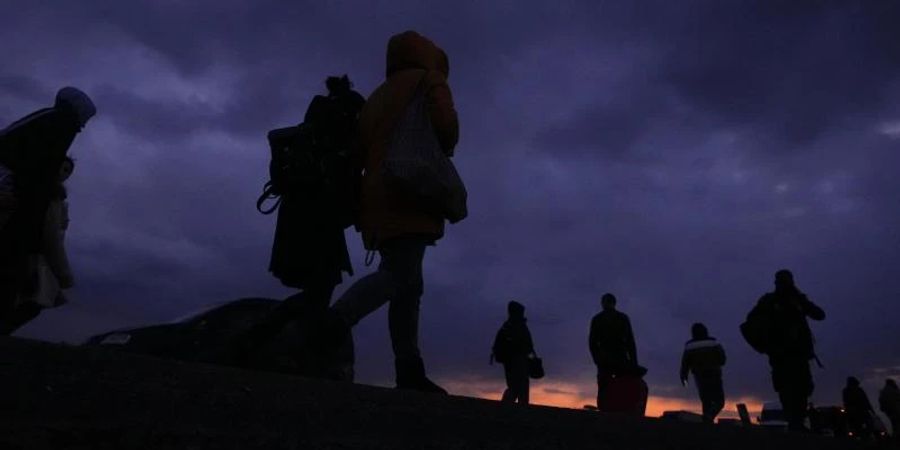 Flüchtlinge, die vor dem Konflikt in der benachbarten Ukraine geflohen sind, gehen mit ihrem Gepäck eine Strasse in Polen entlang. Foto: Petr David Josek/AP/dpa