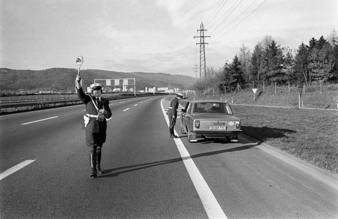 Eine Polizeipatrouille kontrolliert ein Auto an einem der autofreien Sonntage im November/Dezember 1973 in der Schweiz. autofreier Sonntag Benzinpreis