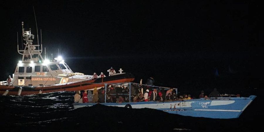 Ein Schiff der Küstenwache fährt zu dem völlig überfüllten Holzboot vor Lampedusa. Foto: Pau De La Calle/AP/dpa