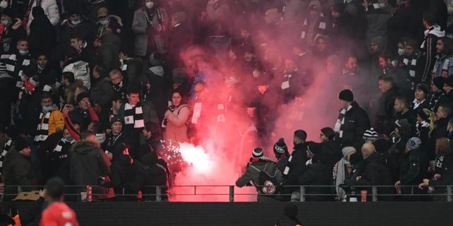 Ein Feuerwerkskörper, der von Fans von Royal Antwerpen geworfen worden ist, brennt auf der Gegentribüne ab. Foto: Arne Dedert/dpa