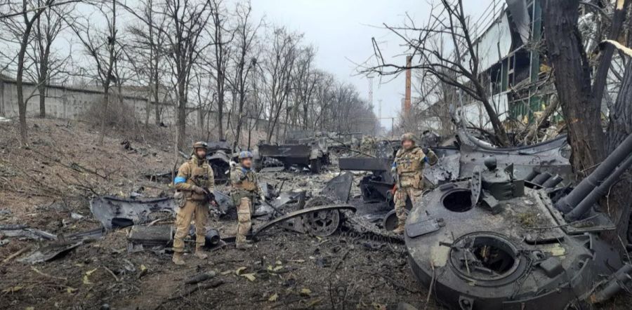 Kämpfer des Asow-Regiments posieren im Ukraine-Krieg in Überresten von russischen Militärfahrzeugen.