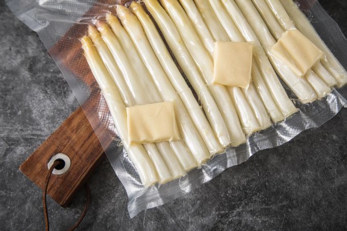 Zum Einfrieren sollte der Spargel weder gekocht noch blanchiert werden. Spargelliebhaber, die nicht genug von dem Edelgemüse bekommen können, kaufen die Stangen zum Einfrieren am besten gleich nach Pfingsten. Da gibt es den meisten. Danach wird er meist wieder teurer. Spargel eingeschweisst Sauce Hollandaise Holzbrett