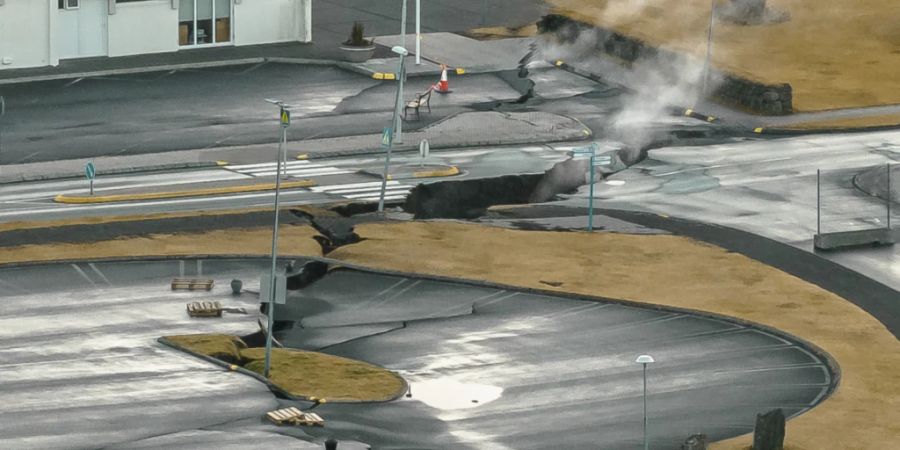 Aus Rissen im Boden neben einem Kinderspielplatz in der isl‰ndischen Stadt GrindavÌk steigt Rauch auf. Foto: Bjorn Steinbekk/AP/dpa