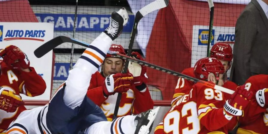 William Lagesson (l) von den Edmonton Oilers wird von Sam Bennett von den Calgary Flames über die Bande gecheckt. Foto: Jeff Mcintosh/The Canadian Press/AP/dpa