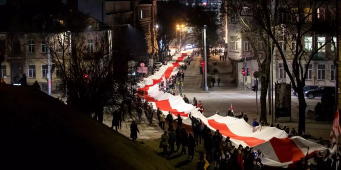 Menschen tragen eine riesige historische Flagge von Belarus anlässlich des belarussischen «Tag der Freiheit». «Tag der Freiheit» in Belarus - Solidarität in Litauen