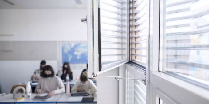 Schüler und Schülerinnen der Klasse 21-M2.21 der Wirtschaftsschule KV Zürich arbeiten Maske tragend selbstständig während des Deutschunterrichts, das Fenster ist zum Lüften während des Unter Coronavirus Schulzimmer lüften