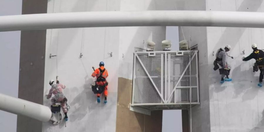 Spezialisten klettern an der Aussenseite des «Spinnaker Towers» und streichen den Aussichtsturm im Hafen. Foto: Andrew Matthews/PA Wire/dpa