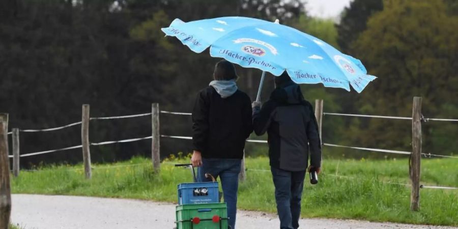 Nur zu zweit hat es diese Männer mit Getränke-Anhänger und Schirm in die Natur gezogen. Foto: Angelika Warmuth/dpa