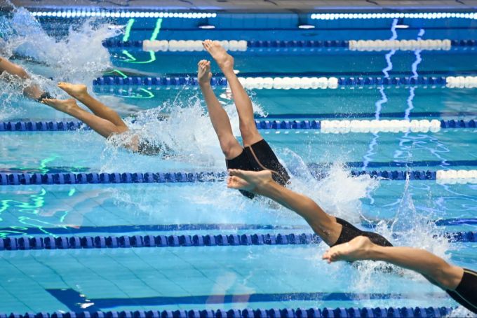 Schwimmer springen bei einem Wettkampf ins Wasser. (Symbolbild) Schwimmen