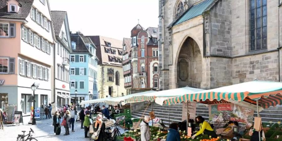 Passanten gehen in der Fussgängerzone an Marktständen vorbei. Foto: Bernd Weissbrod/dpa