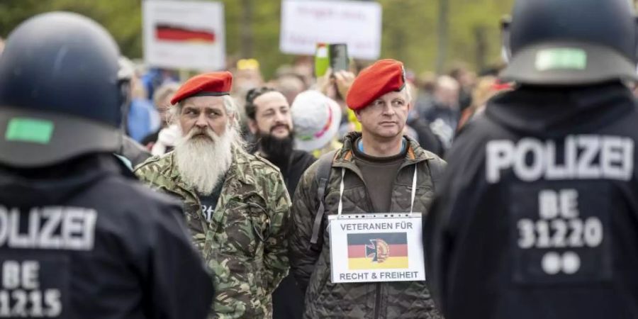 Zwei Demonstranten stehen mit einem Schild - «Veteranen für Recht und Freiheit» - auf der Strasse des 17. Juni in Berlin. Foto: Fabian Sommer/dpa