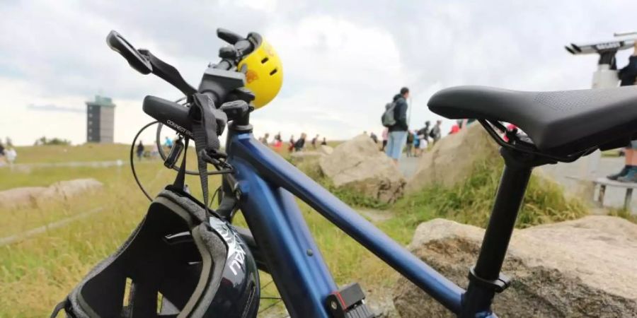 Zwei Helme hängen an einem Fahrrad, das auf dem Brocken steht. Foto: Matthias Bein/dpa-Zentralbild/dpa