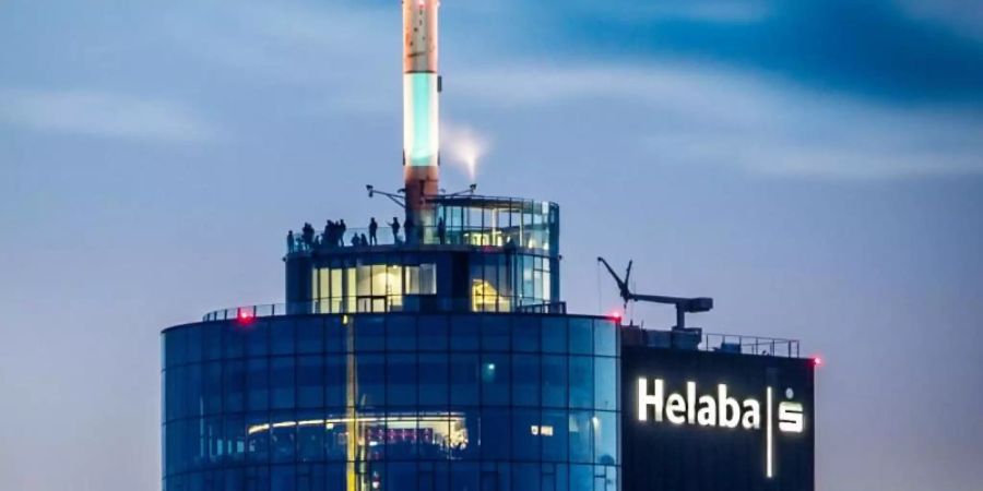 Besucher stehen abends auf der Aussichtsterrasse des Main Towers, der auch die Landesbank Hessen-Thüringen (Helaba) beherbergt. Die drittgrösste Landesbank erwartet 2021 ein Gewinnplus. Foto: Frank Rumpenhorst/dpa