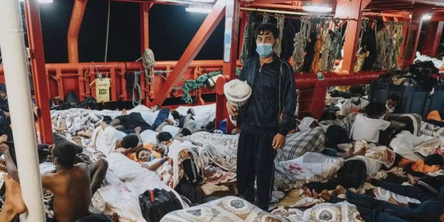 Schlafende Menschen an Deck der "Ocean Viking". Das Rettungsschiff mit mehr als 570 Migranten an Bord darf in den Hafen der Stadt Augusta auf Sizilien. Foto: Flavio Gasperini/SOS Mediterranee/AP/dpa