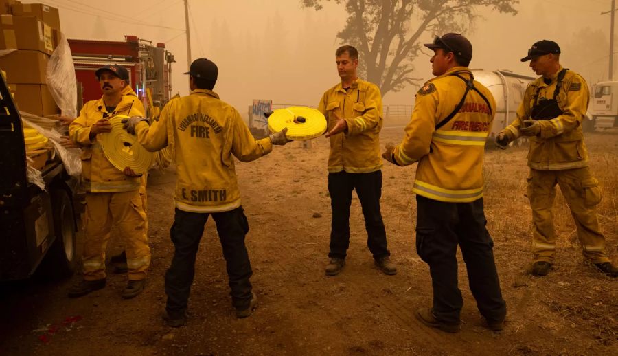 Feuerwehrleute entladen Schlauchleitungen bei der Bekämpfung des Dixie-Feuers in Greenville, Kalifornien, USA, am 07. August 2021.