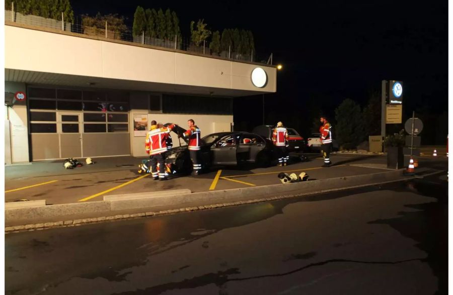Abgebranntes Auto auf einem Parkplatz umgeben von Feuerwehrleuten - zvg Kantonspolizei St. Gallen