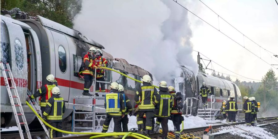 Feuerwehrleute löschen einen brennenden ICE-Wagen, der auf der Schnellstrecke zwischen Frankfurt und Köln Feuer gefangen hatte.