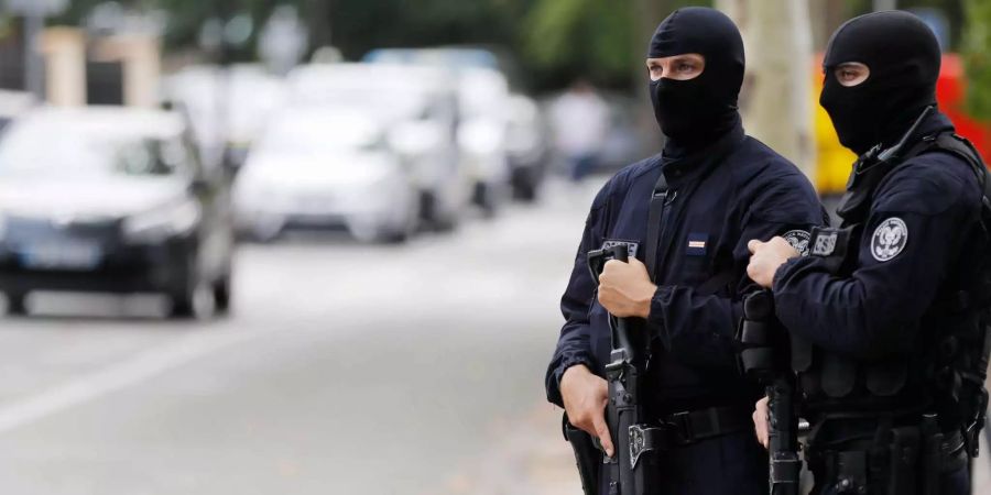 Zwei französische Polizisten sind maskiert und beobachten am Strassenrand das Geschehen.