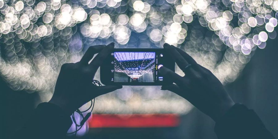 Eine Person fotografiert eine Beleuchtung mit dem Handy.