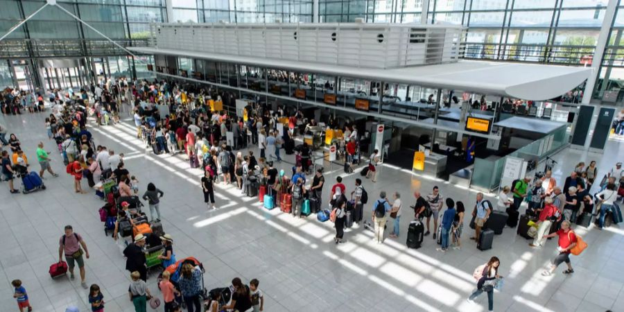 Fluggäste stehen in langen Schlangen an Check-In-Schaltern im Terminal 2 am Flughafen in München.
