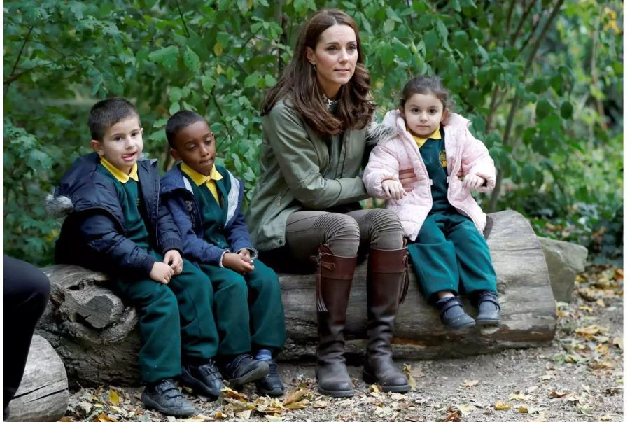 Herzogin Kate sitzt mit Kindern auf einem Baumstamm, während sie die Sayers Croft Waldschule und den Wildlife Garden am Paddington Recreation Ground in London besucht.