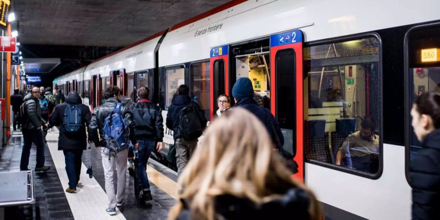 Pendler steigen am Bahnhof in einen Zug ein und aus.