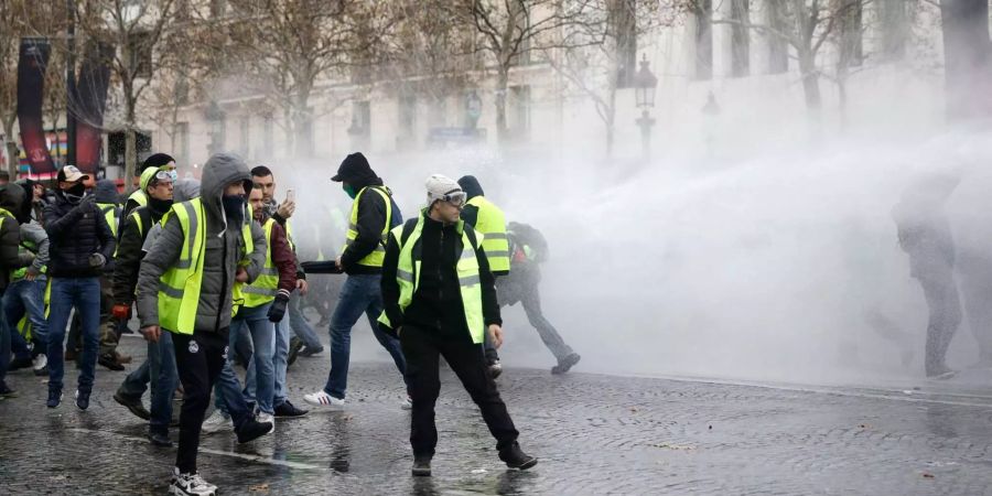 Demonstranten werden auf der Champs-Elysees-Allee von einem Wasserwerfer getroffen.