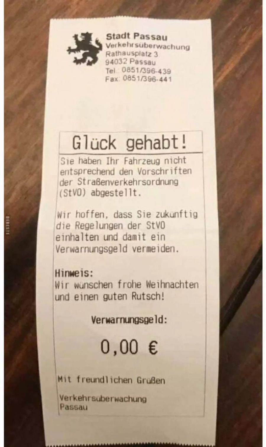 Ein Strafzettel auf einem Holztisch.