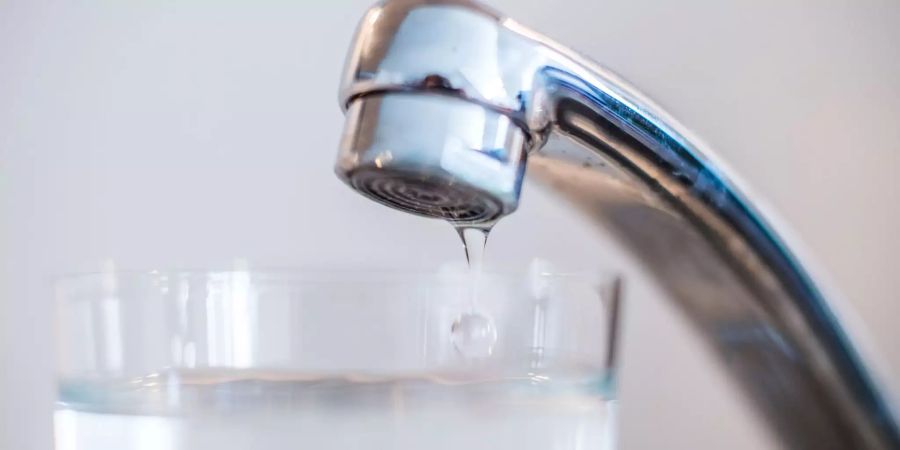 Ein Glas steht unter einem Wasserhahn.