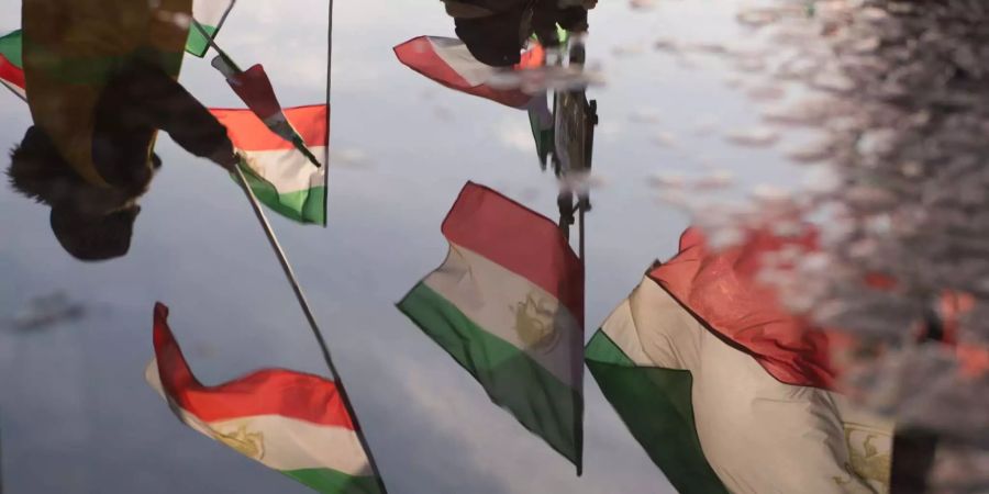 Iranische Fahnen reflektieren in einer Pfütze.