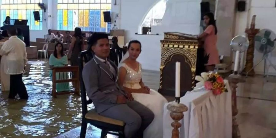 Jobel Delos Angeles und ihr frischgebackener Mann sitzen vor dem Altar der überfluteten Kirche in Hagonoy (PHL).