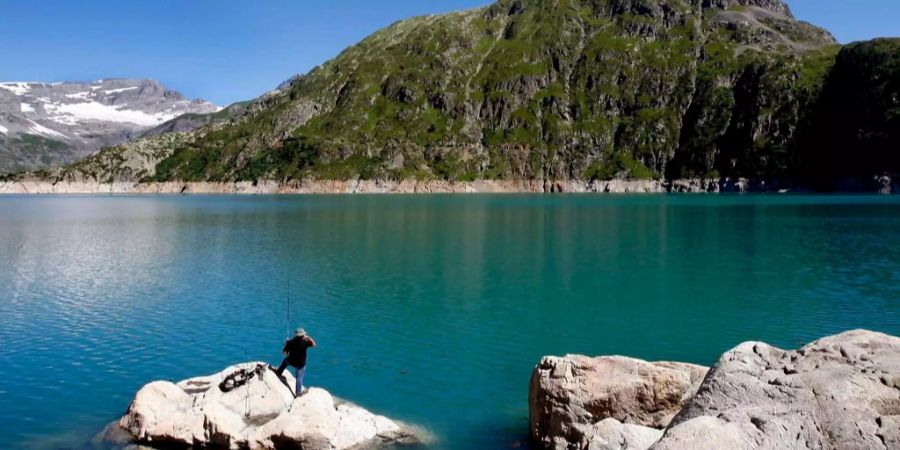 Ein Fischer geniesst das schöne Wetter am See Emosson im Kanton Wallis.