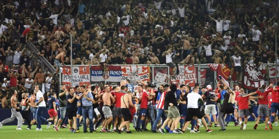 Fans des Fussballvereins Roter Stern Belgrad stürmen den Platz.