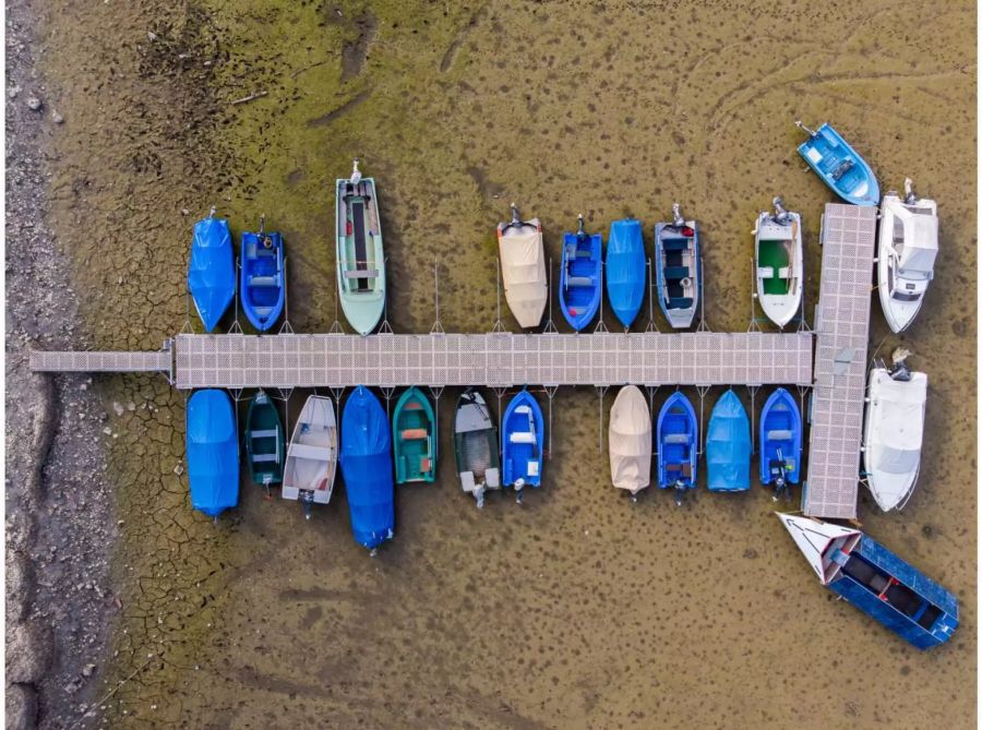 Auf dem Trockenen liegen Boote an einem Steg am Ufer des ausgetrockneten Lac des Brenets im Jura.