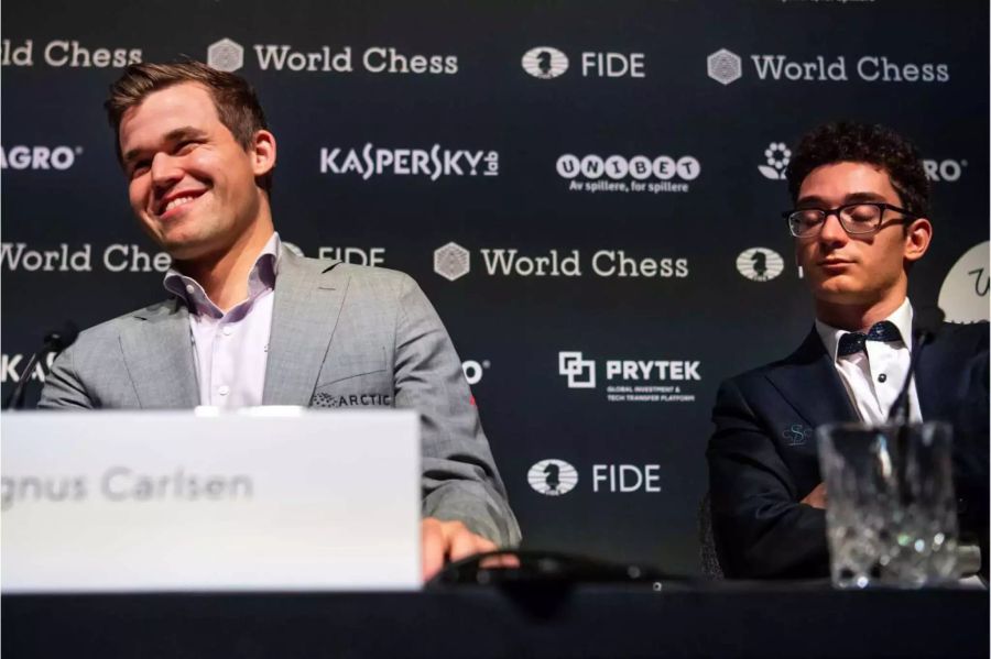 Der amtierende Schachweltmeister Magnus Carlsen (l) freut sich bei der Pressekonferenz über seinen Sieg im Tie-Break gegen Herausforderer Fabiano Caruana (r).