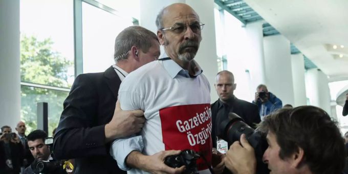 Der Fotograf wird wegen des T-Shirts mit der Aufschrift «Pressefreiheit für Journalisten in der Türkei» aus der Pressekonferenz von Merkel und Erdogan geführt. Der Fotograf wird wegen des T-Shirts mit der Aufschrift «Pressefreiheit für Journalisten in der Türkei» aus der Pressekonferenz von Merkel und Erdogan geführt.