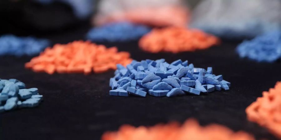 Bunte MDMA Drogen liegen gehäuft auf einem Tisch.