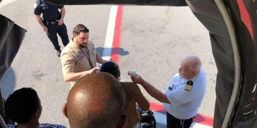 Einem Passagier wird beim Verlassen des aus Dubai kommenden Emirates-Flugzeugs am JFK Airport in New York die Temperatur gemessen.