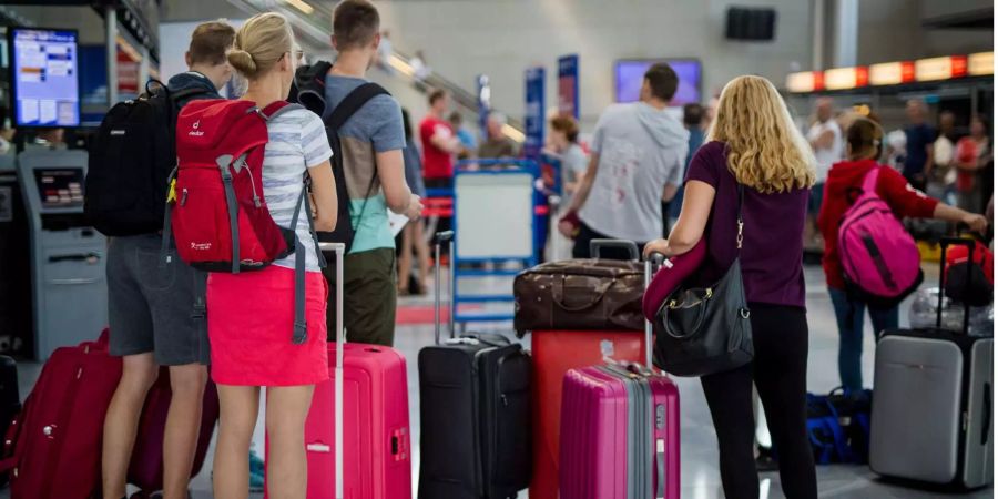 Passagiere warten in einem Terminal darauf, ihr Gepäck an einem Check-In-Schalter abzugeben.