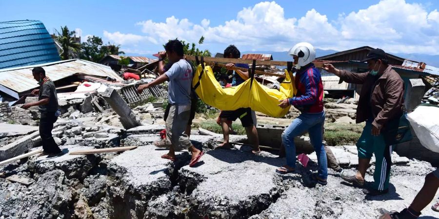 Helfer tragen die Leiche eines Opfers nach dem Erdbeben in Indonesien.