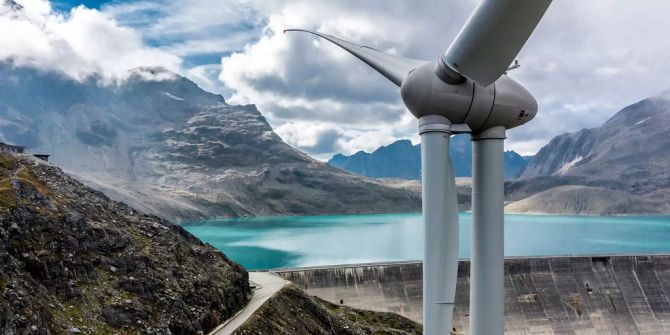 Die Staumauer Griessee mit einer Windturbine.