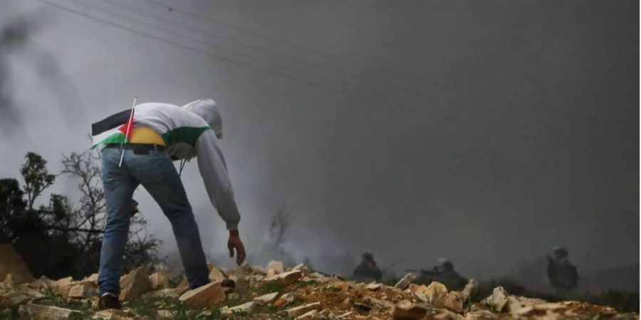 Palästinenser wirft Steine nach Soldaten.