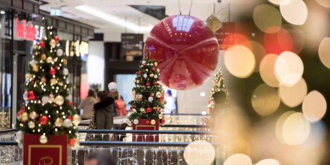 Kunden gehen durch ein weihnachtlich geschmücktes Einkaufszentrum.