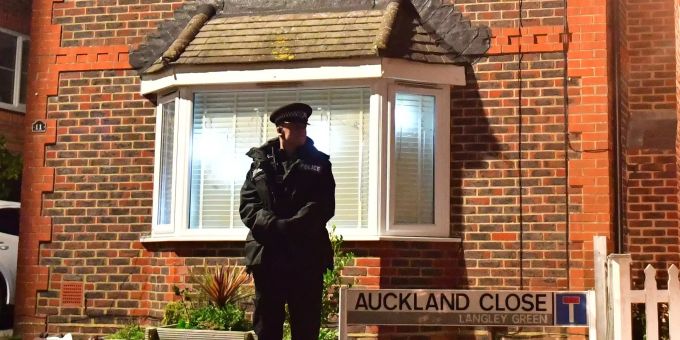 Die Polizei steht nach dem Drohnen-Alarm in Gatwick stark in der Kritik. Ein Polizist steht vor einem Haus.