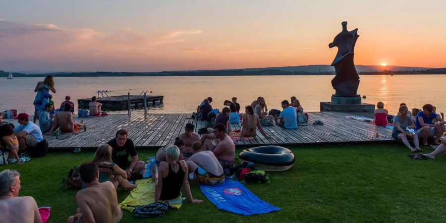 Menschen geniessen den Sonnenuntergang am Seebad Seeliken