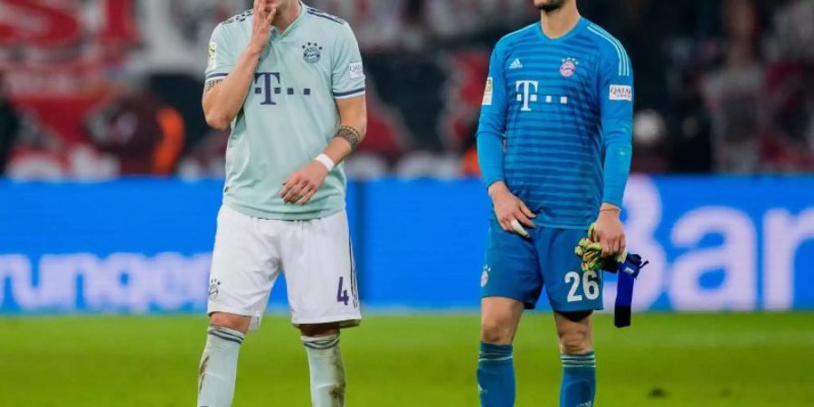 Bayerns Niklas Süle (l) und Torwart Sven Ulreich stehen nach der Niederlage in Leverkusen resigniert auf dem Rasen. Foto: R. Vennenbernd