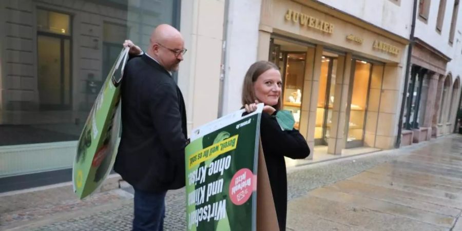 Wolfgang Wetzel, (l) Spitzenkandidat der Grünen und Christin Furtenbacher, Landesvorstandssprecherin der Grünen in Sachsen, laufen mit Wahlplakaten durch die Innenstadt von Zwickau. Foto: Bodo Schackow/dpa-Zentralbild/dpa
