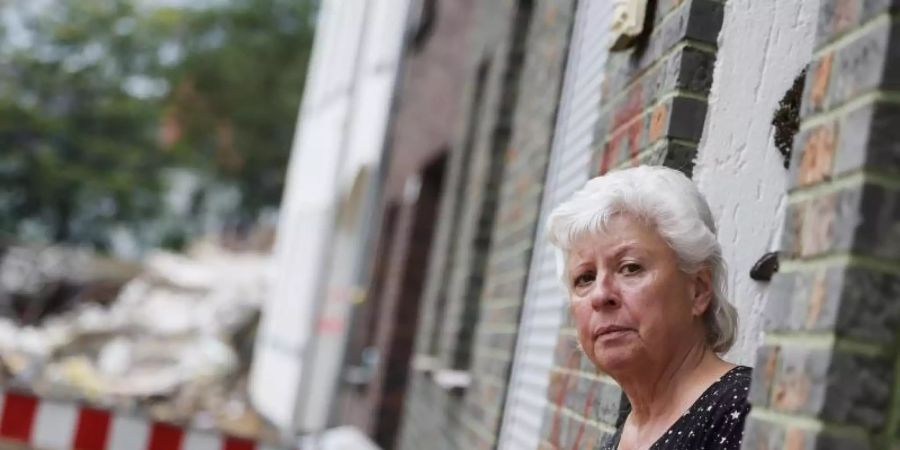 Maria Dunkel, Anwohnerin in Erftstadt-Blessem, blickt aus dem Eingang ihrer Wohnung. In Erftstadt tat sich in der Nacht zum 15. Juli die Erde auf und verschlang mehrere Häuser. Foto: Oliver Berg/dpa