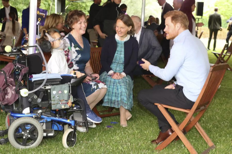 Prinz Harry unterhält sich mit einer Familie beim Wohltätigkeitsevent.